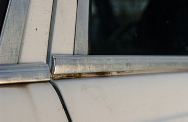 Chrome list on an old, white car door.