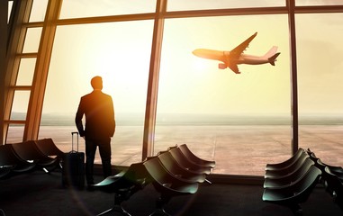 Businessman standing at the airport window waiting for departure