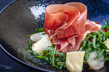 Fresh Salad with jamon rucola and parmesan. Spanish cuisine. Close up. Copy space. Concept of healthy food. Lunch or tasty appetizer. Summer menu. Homemade salad bowl