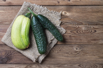 Trendy ugly organic natural cucumber and squash on napkin, on natural wooden background. Copy space.