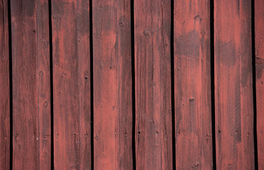 A weathered, old, wooden wall with vertical panelling.