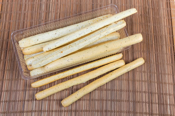 Breadsticks with Italian herbs in container on bamboo table mat