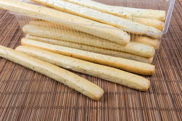 Breadsticks with Italian herbs in transparent container close-up