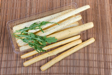 Breadsticks with Italian herbs in container with arugula leaves