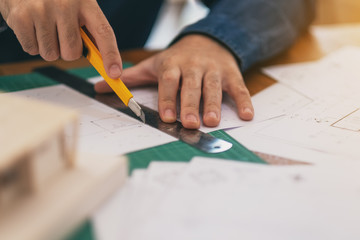 An architect working and cutting papers in office
