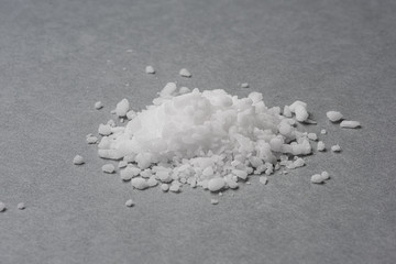 Small pile of salt crystals on grey background.