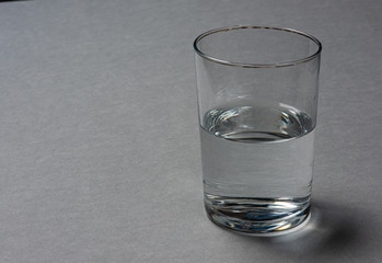 Half empty glass of water  on grey background.