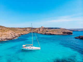 White yacht stands in azure transparent water sea, beach Blue Lagoon Comino Malta. Aerial view - obrazy, fototapety, plakaty