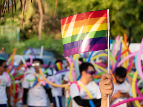 LGBT pride month background. a spectator waves a gay rainbow flag at LGBT gay pride parade festival in Thailand