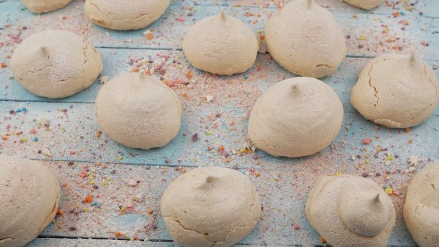 Meringues are lying on a pale blue wooden board, background