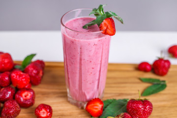Glass with tasty strawberry smoothie on wooden table