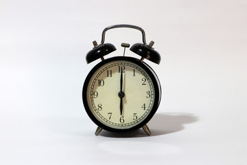 Twin bell alarm clock black color on six o'clock put on the white floor.