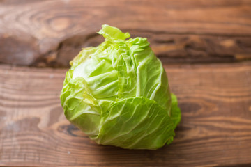 Fresh whole head of young green cabbage on wooden background.