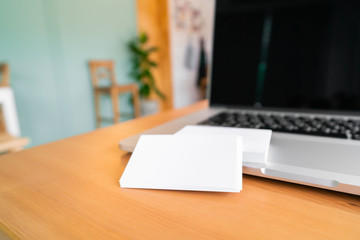 Blank business cards and laptop on wooden surface