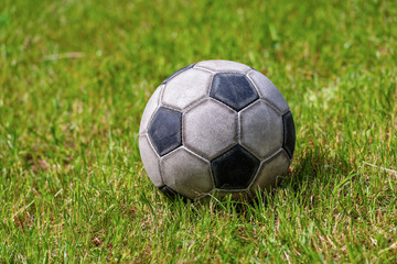 Close-up of an old leather soccer ball on green grass, football sport concept