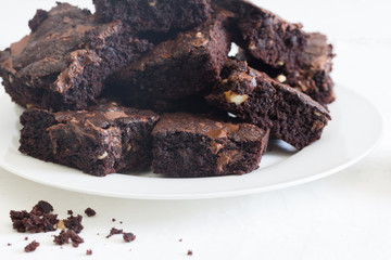 Chocolate brownies in a heap on a white plate - baked chocnut brownies