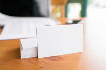 Blank business cards and laptop on wooden surface