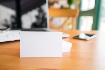 Blank business cards and laptop on wooden surface