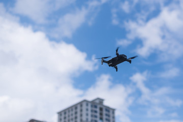 Flying drone against the sky with clouds and buildings.