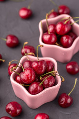 ripe and juicy cherries in a pink plate and scattering, the shape of star. Gray, cement table, postcard