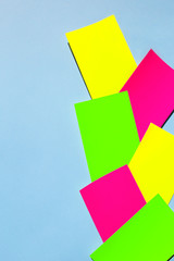 Neon colorful sticky note paper on blue background. Copy space for your text. Flat lay, top view. 