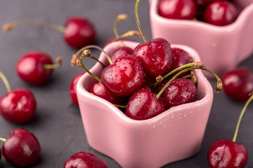 ripe and juicy cherries in a pink plate and scattering, the shape of star. Gray, cement table, postcard