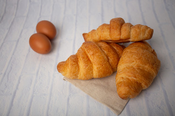 Croissants with coffee cups with flour and eggs on a white background, breakfast, brown bread, morning drinks, fantasy world: delicious food for health, pastries, bakery, restaurants, lifestyle areas