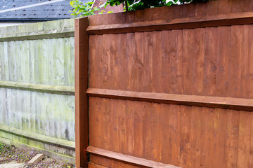 Painting old wooden fence with a brown paint, renovation concept, before and after image