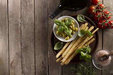Top view of delicious olives with other products on wooden surface