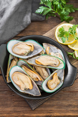 Raw kiwi mussels on a wooden Board on a wooden table. Rustic style