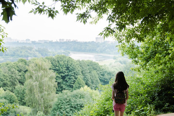 Young girl traveller with a small backpack, while enjoying the amazing views of the city, walking and exploring nature . Expectation.