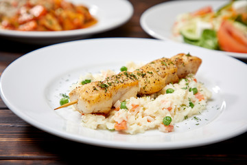 chicken kebab with rice and vegetables on the wooden background