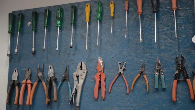 Several tools hanging on a blue wall. The image is in closeup.
