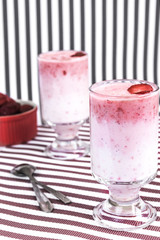 Vegetarian coconut milk cocktail with strawberry in white glass on striped background