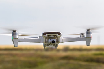 Professional filming drone flies in the air at a low altitude against a blue sky. Drone makes...