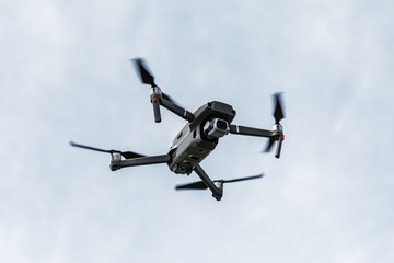 Professional filming drone flies in the air at a low altitude against a blue sky. Drone makes photos. Modern new technology. Ready background with place for your text