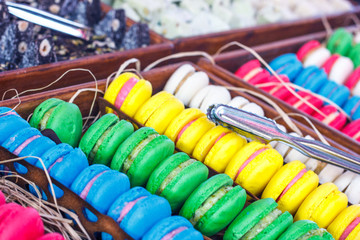 Colorful macaroons. Traditional sweets with silver tongs