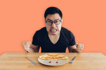 Angry and mad face of man is eating homemade breakfast set of omelet.