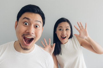 Surprised and shocked couple lover in white t-shirt and grey background.