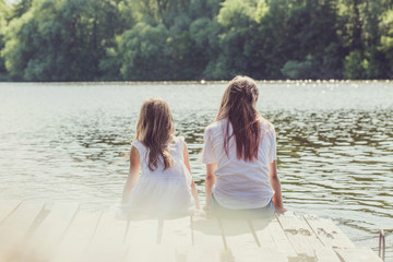 Girls sitting on the pier, back view