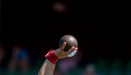 Man Lifting Shot Put at a Track and Field Meet