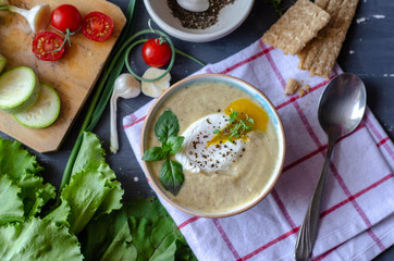 Healthy zucchini cream soup served with poached egg and greens. Proper nutrition food