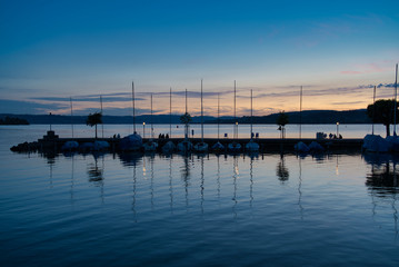 Obraz premium Menschen am Pier vor Segelschiffen und bei Sonnenuntergang
