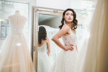 Beautifu bride choosing wedding dress in a wedding salon