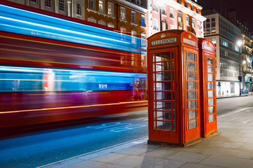 Light trails of a double decker bus next to the iconic telephone booth in London