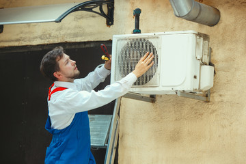 HVAC technician working on a capacitor part for condensing unit. Male worker or repairman in...