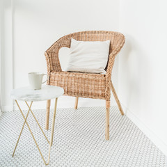 Rattan chair with pillow and marble coffee table at balcony with mosaic floor. Minimal modern bright Scandinavian nordic interior design concept.