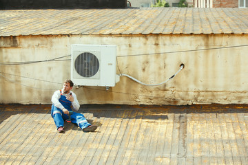 HVAC technician working on a capacitor part for condensing unit. Male worker or repairman in uniform repairing and adjusting conditioning system, diagnosting and looking for technical issues.