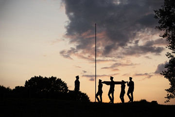 Fototapeta na wymiar Soldiers Raising The Lithuanian Flag At Sunset