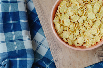 Cornflakes in a pink bowl, on a wooden table. copy space